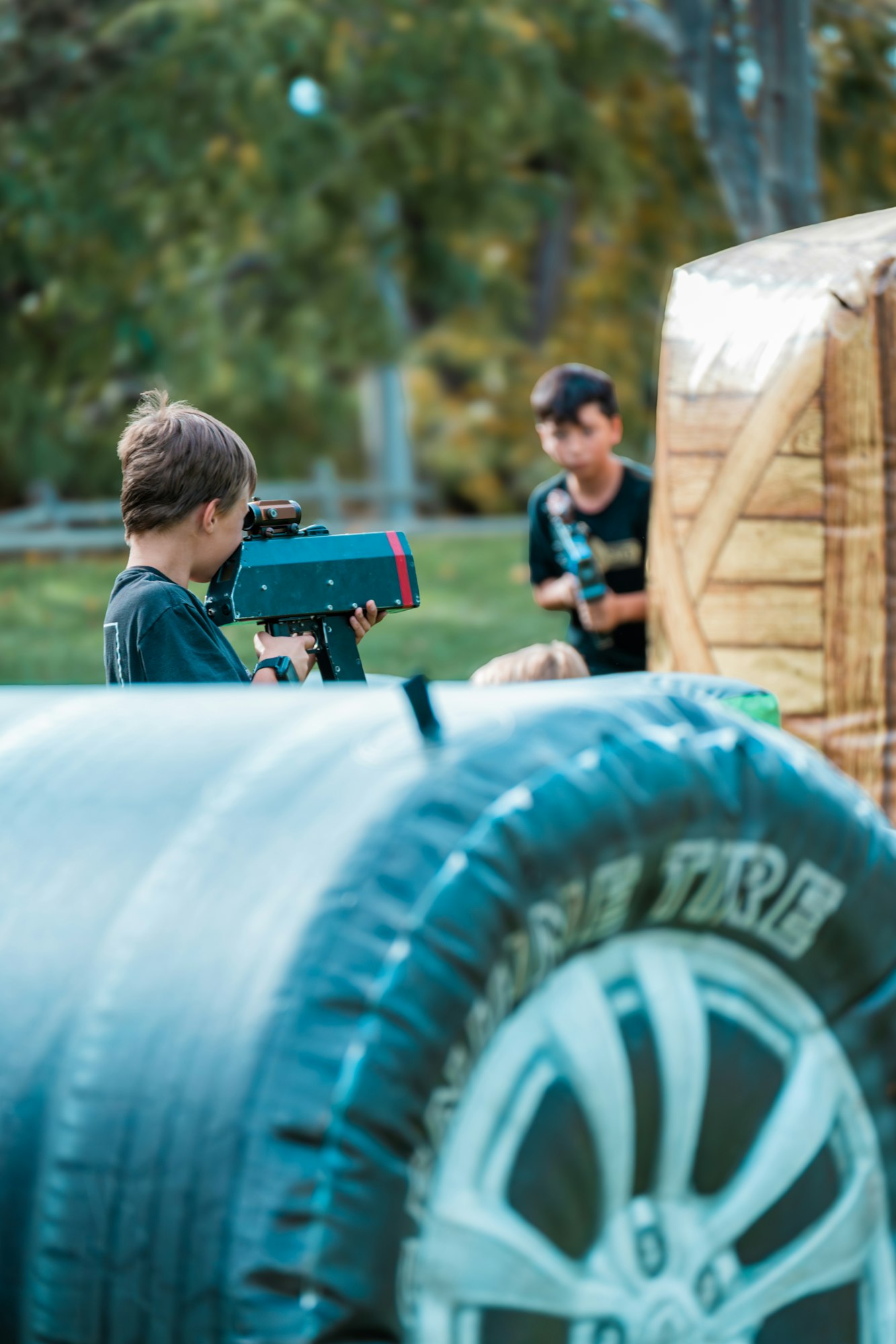 Kids playing laser tag outdoors with inflatable barriers.