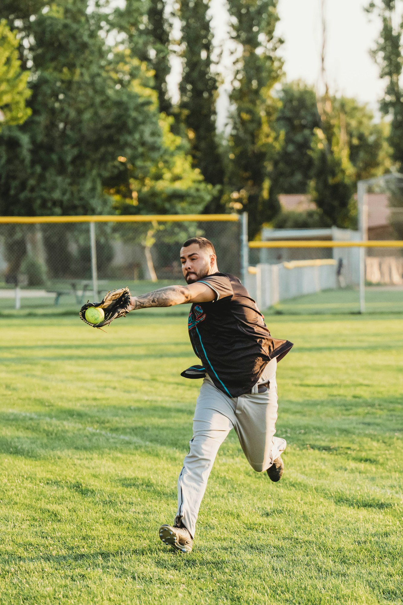 A person throwing a softball in a field.