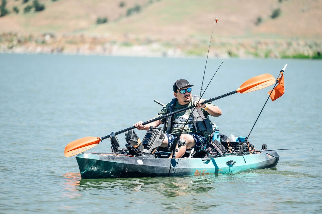 A person kayaking and fishing on a calm lake.