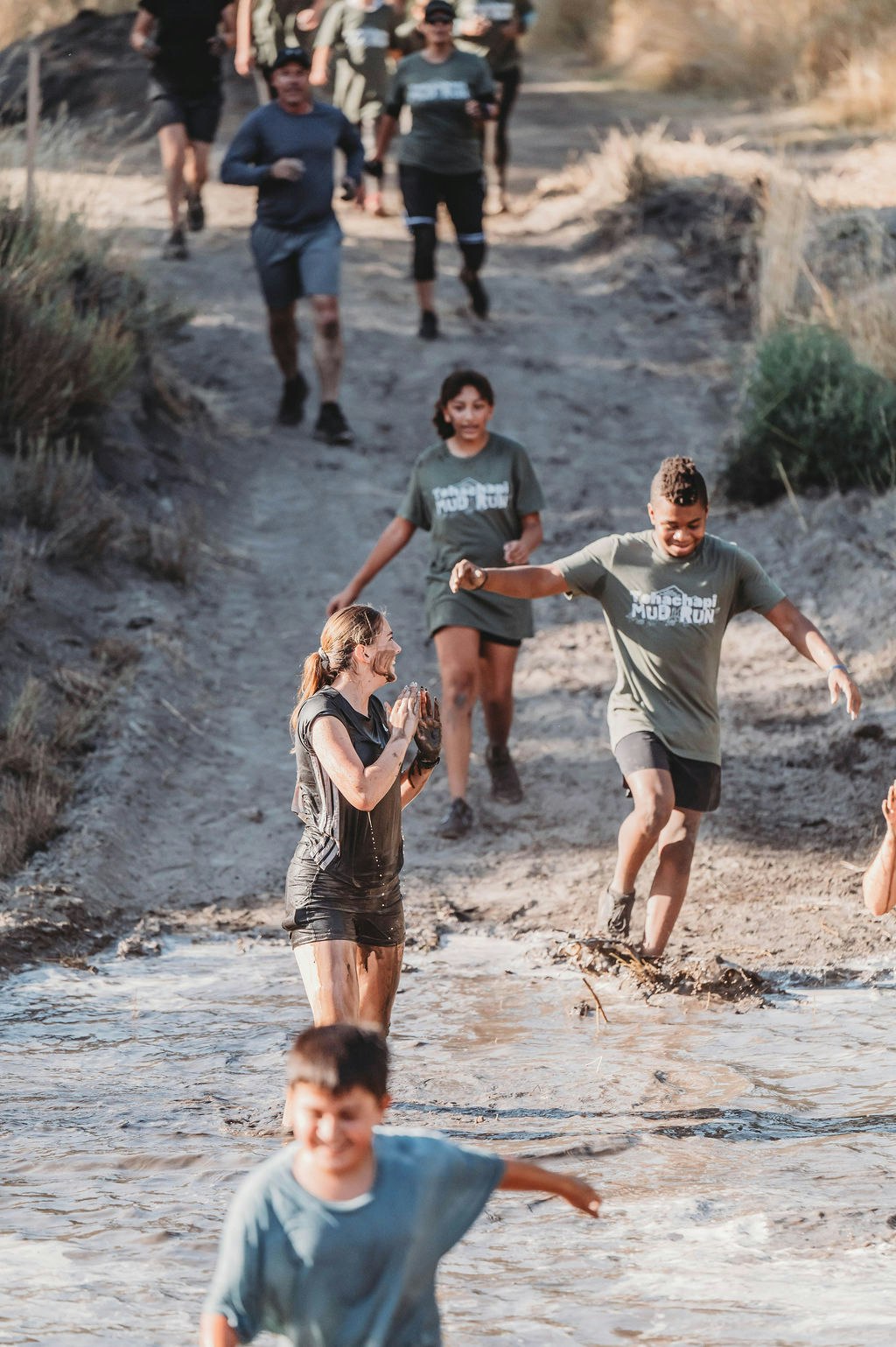 People participating in a muddy obstacle run, having fun.