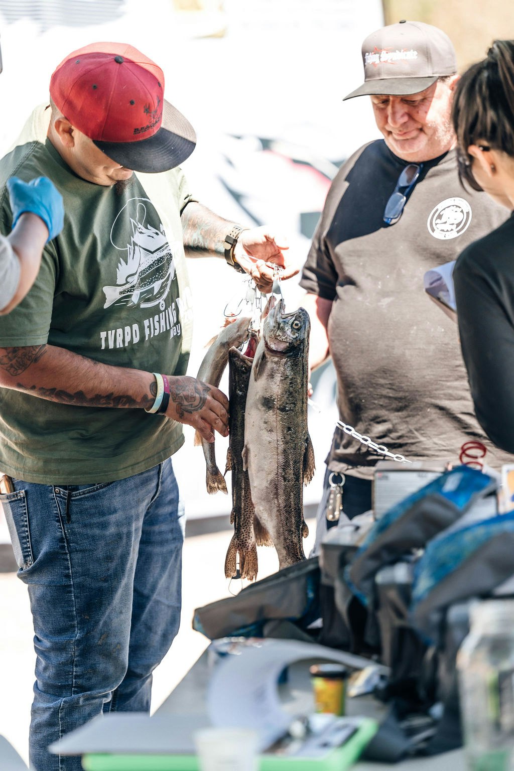 A person is holding a string of fish showing them to others, suggesting a successful fishing trip or a competition.
