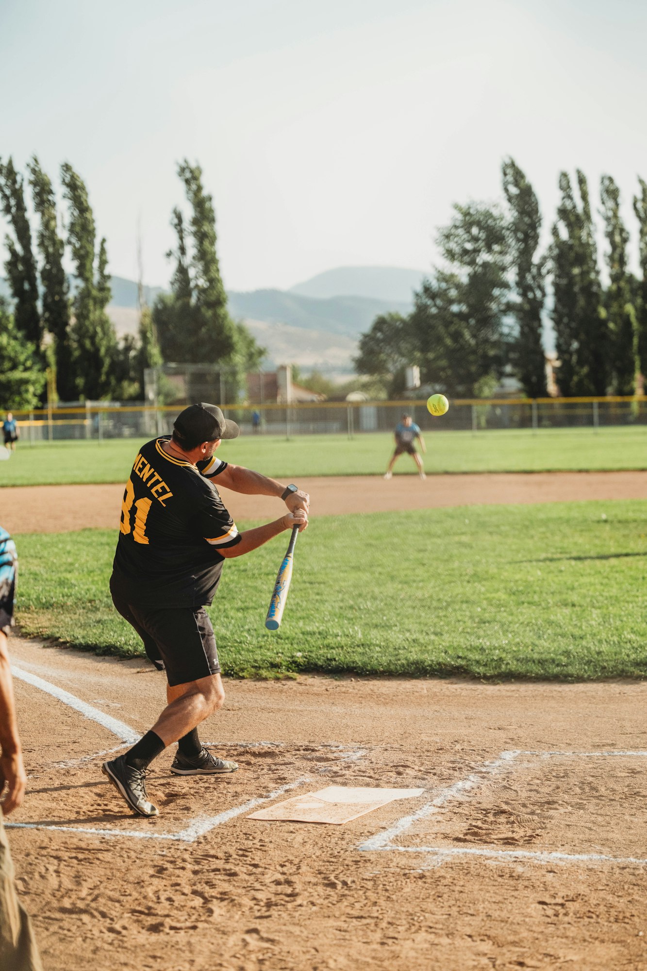A baseball player swinging a bat at a ball on a sunny day.