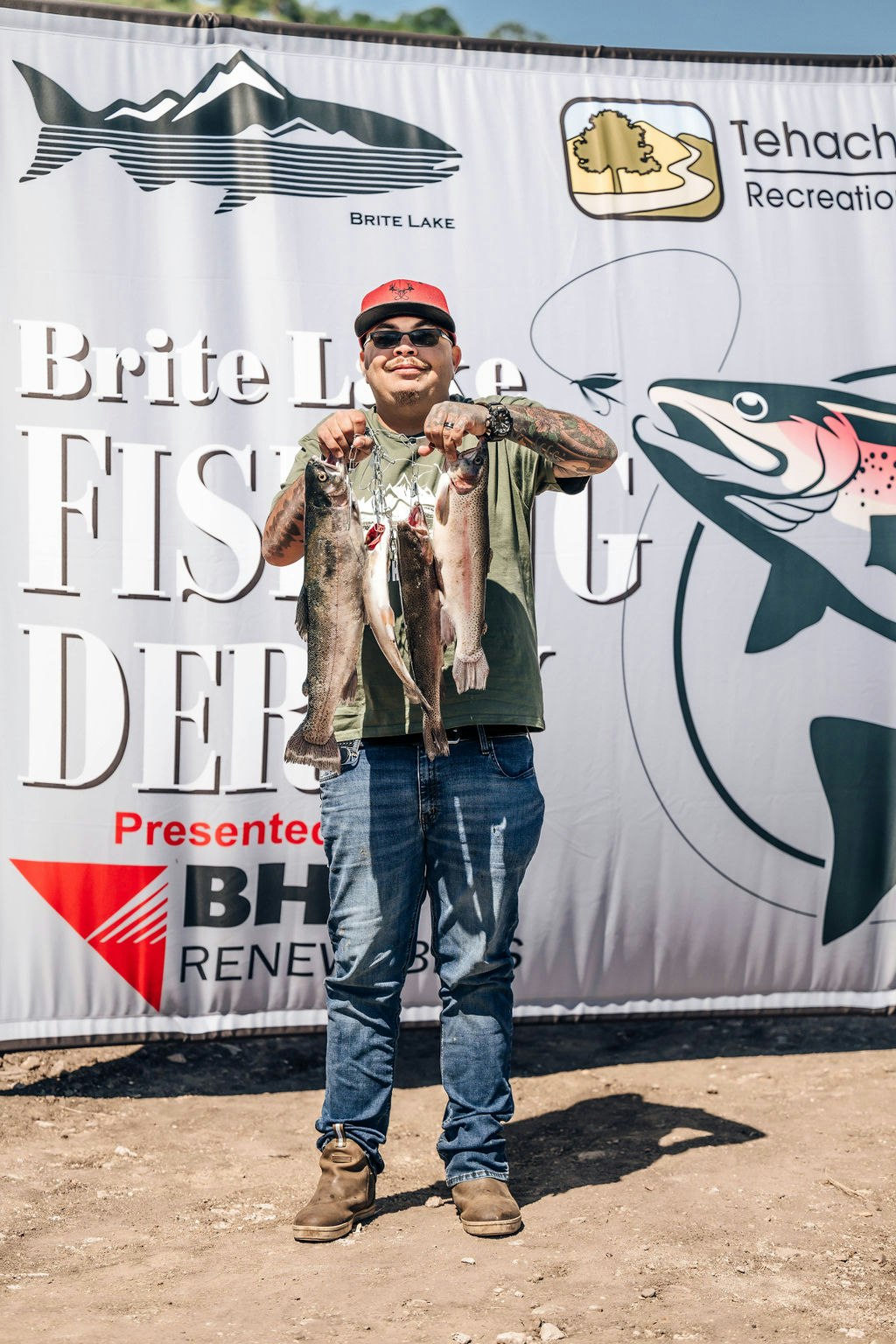 A person proudly holding up two fish at a “Brite Lake Fishing Derby” event.