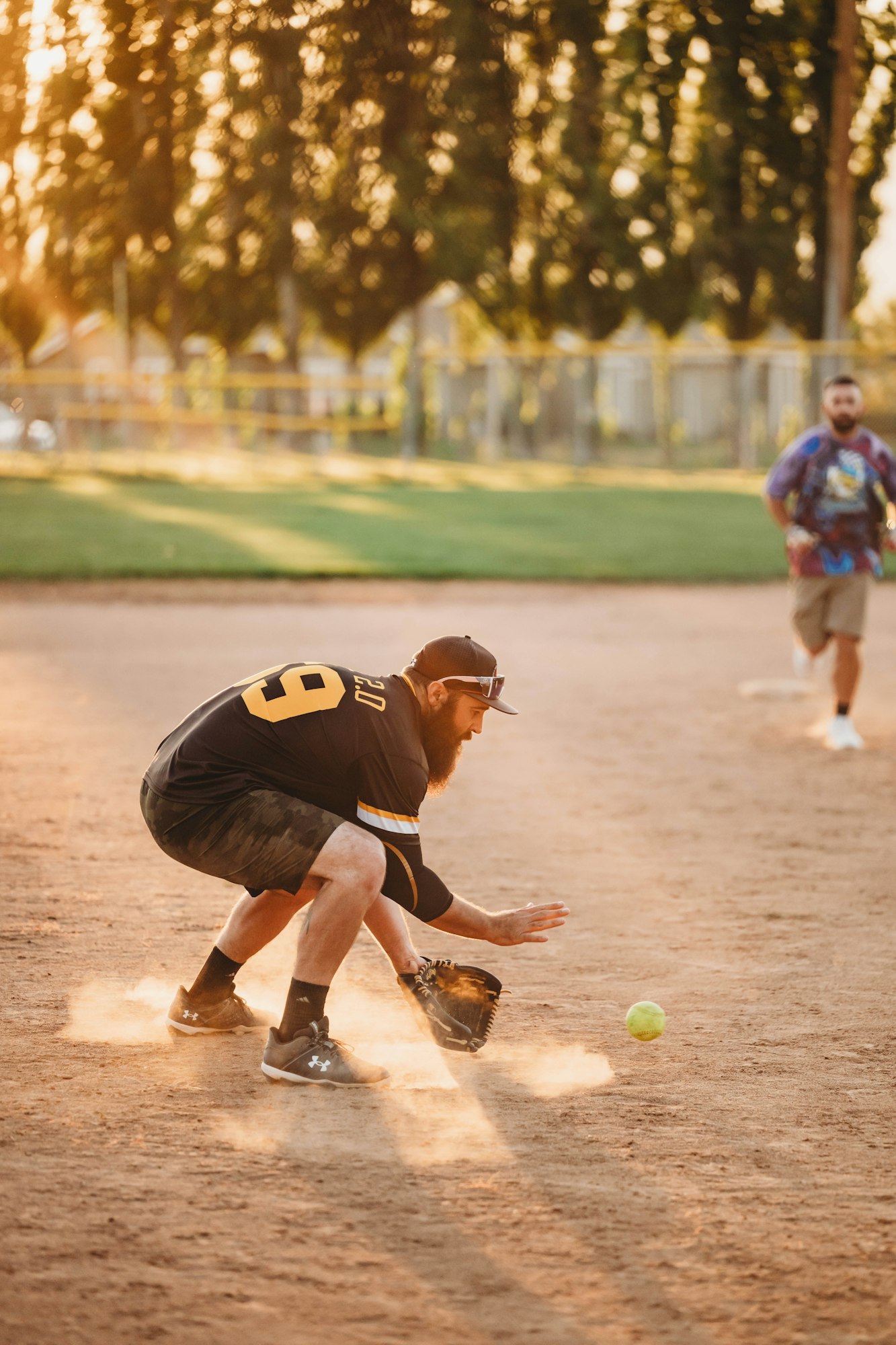 A player fielding a ball during a sunset softball game.