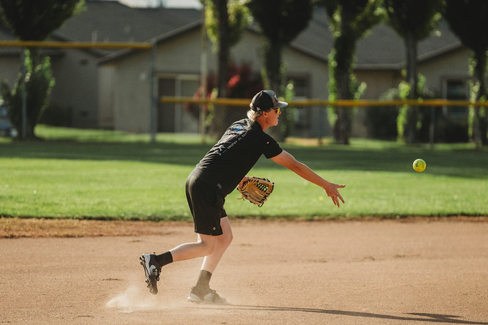 A person playing softball, preparing to catch a ball mid-game.