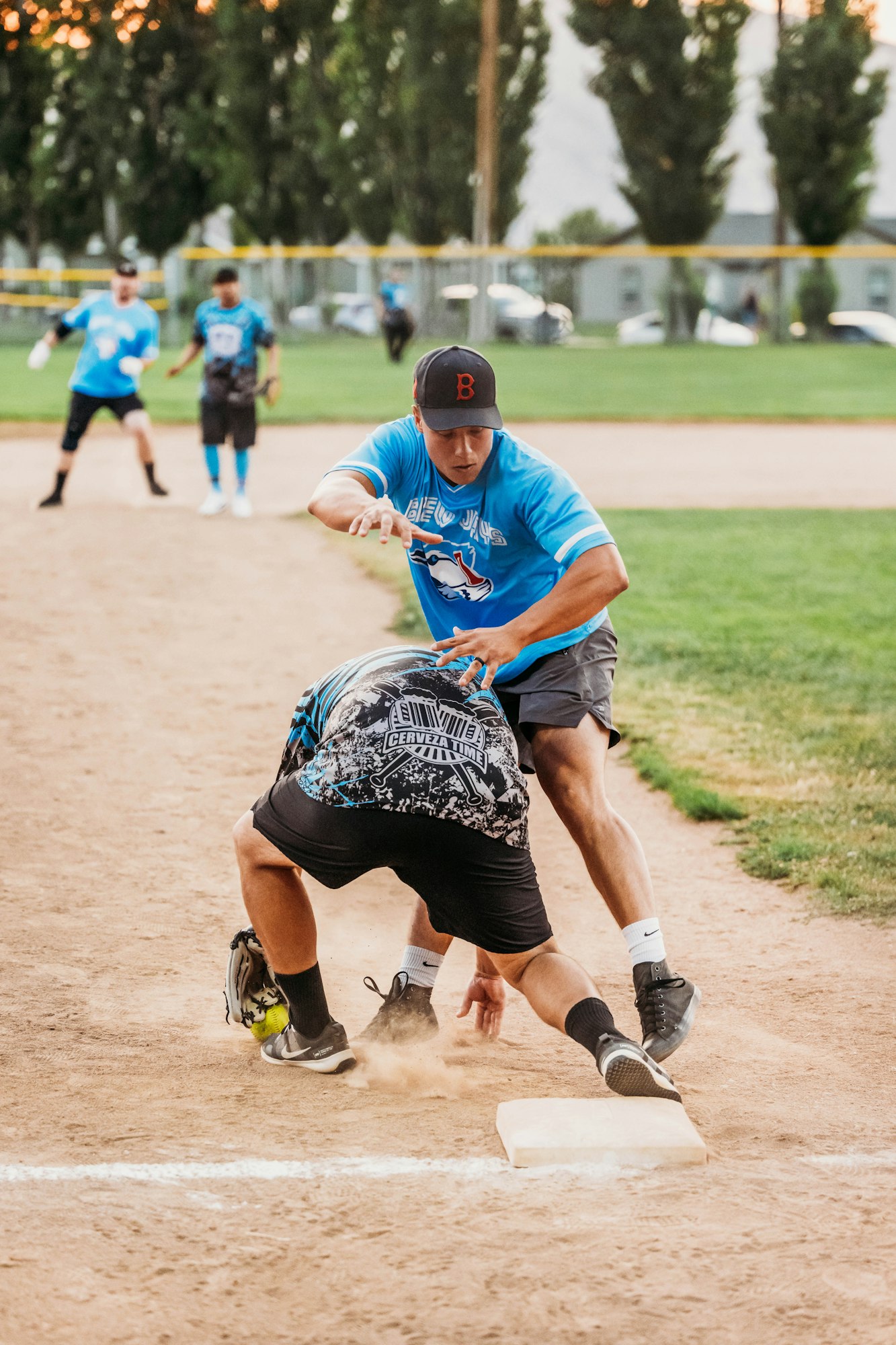A baseball game in action, with a player sliding into a base and another prepared to tag. Dust is kicked up, showing motion.