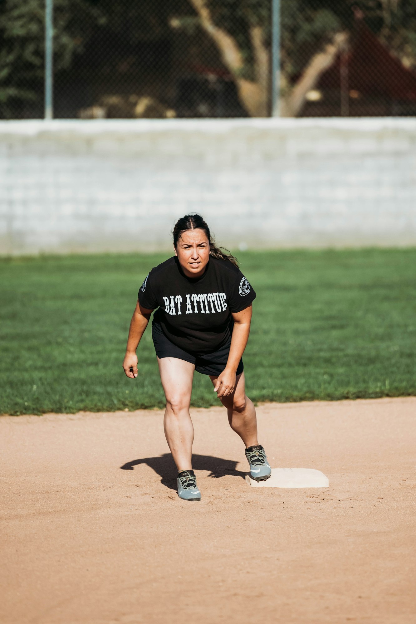 Person playing baseball, focused, standing on base.