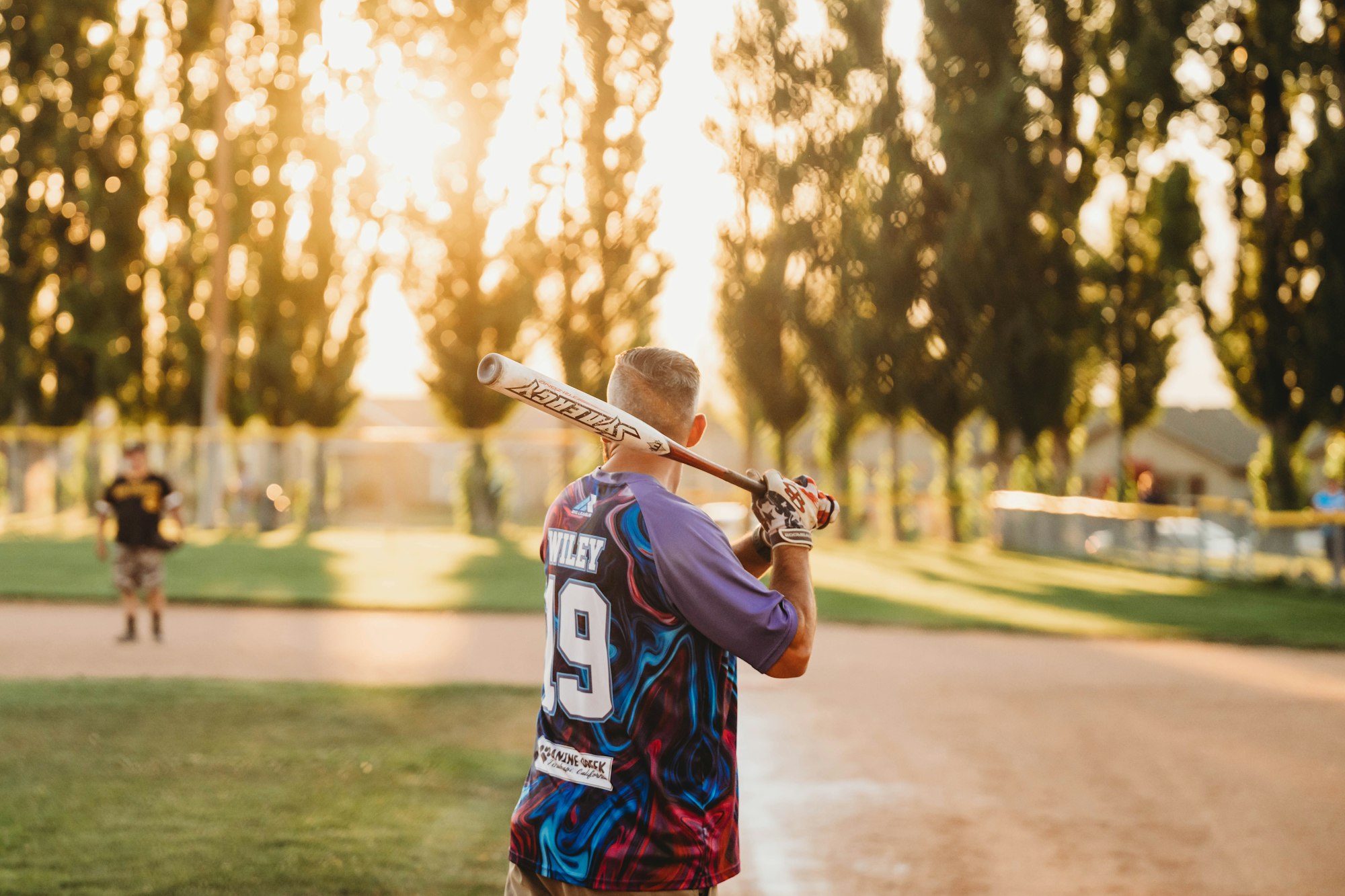 A baseball player ready to bat during a sunny evening game.