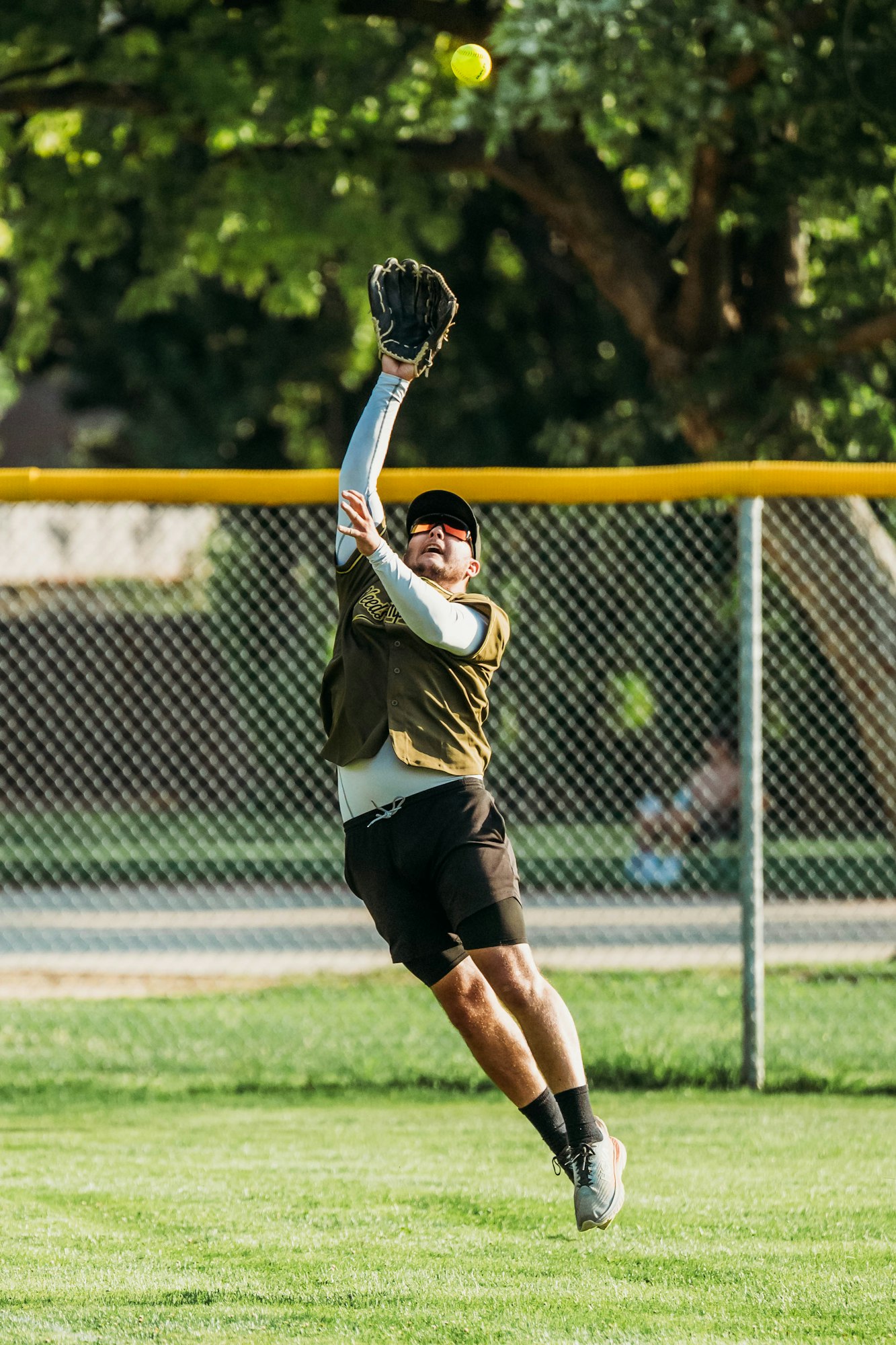 A player reaching for a catch in a softball game.