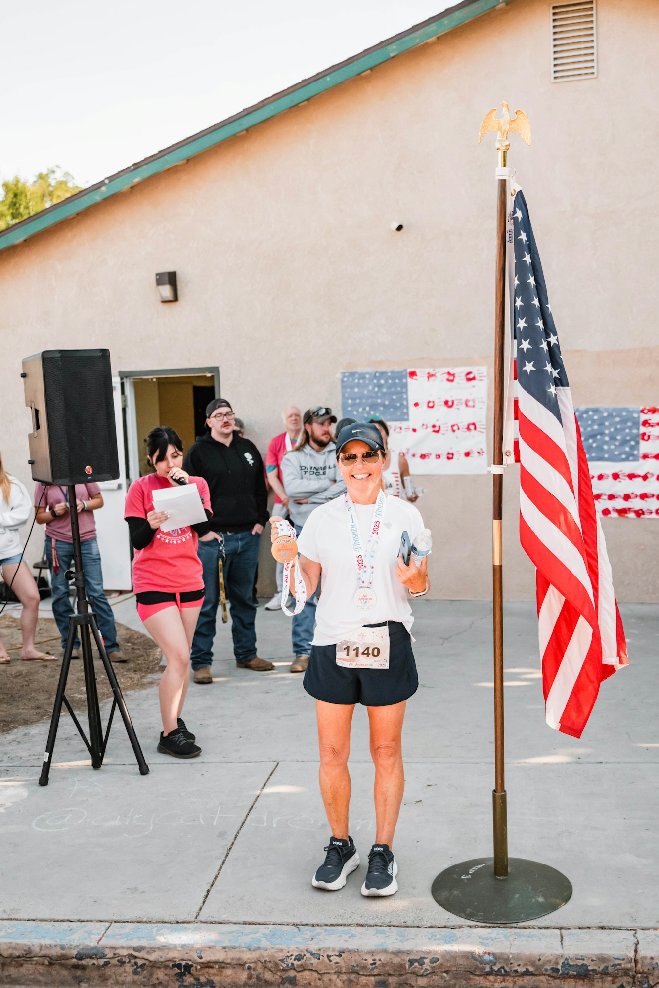 May contain: clothing, shorts, footwear, shoe, electronics, speaker, flag, boy, male, person, teen, tripod, hat, accessories, glasses, adult, female, woman, man, wristwatch, photography, and skirt