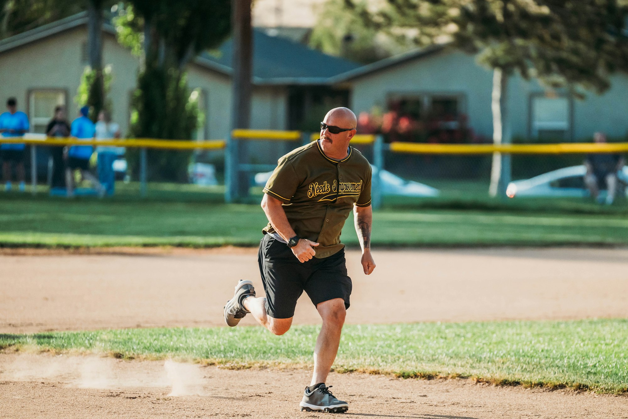 Man in a baseball jersey running on field, with dust trail behind.