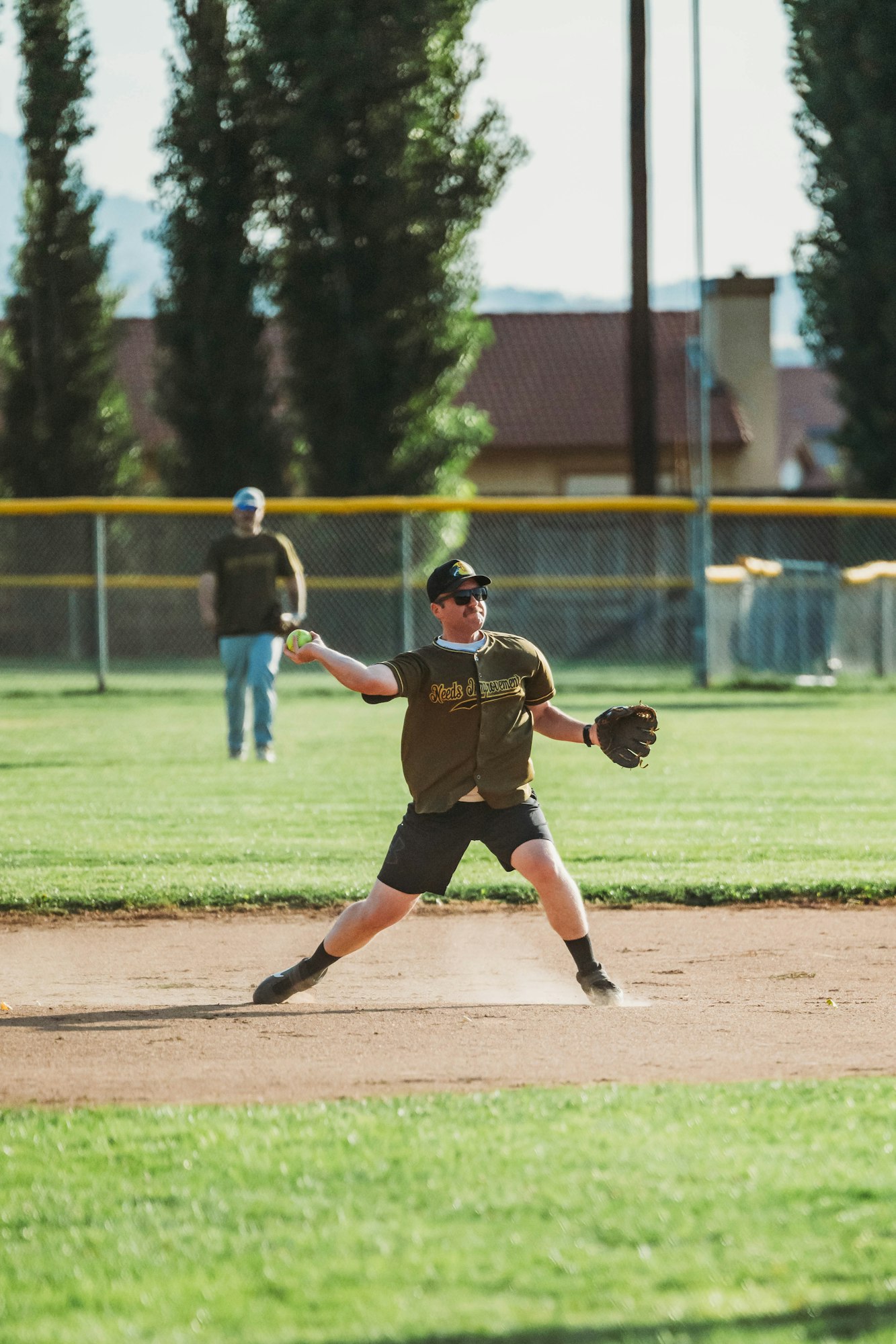 A person playing baseball, throwing the ball on a sunny day.