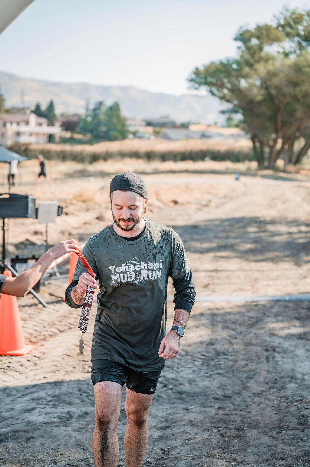 A muddy runner receives a medal after completing the "Tehachapi Mud Run."