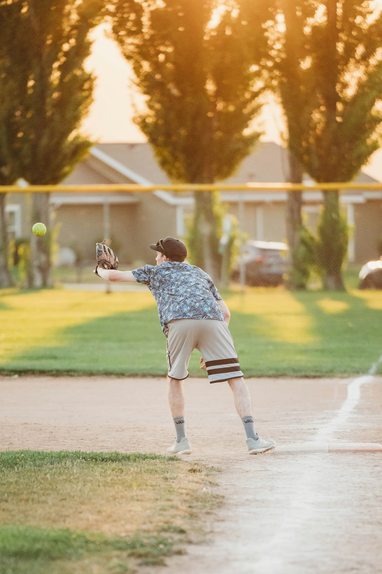 A person playing catch with a baseball glove at sunset.