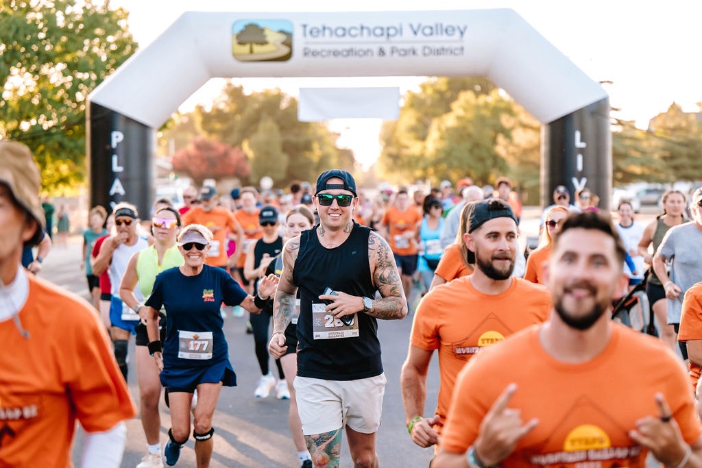 A group of runners participating in a race under a Tehachapi Valley Recreation & Park District archway.