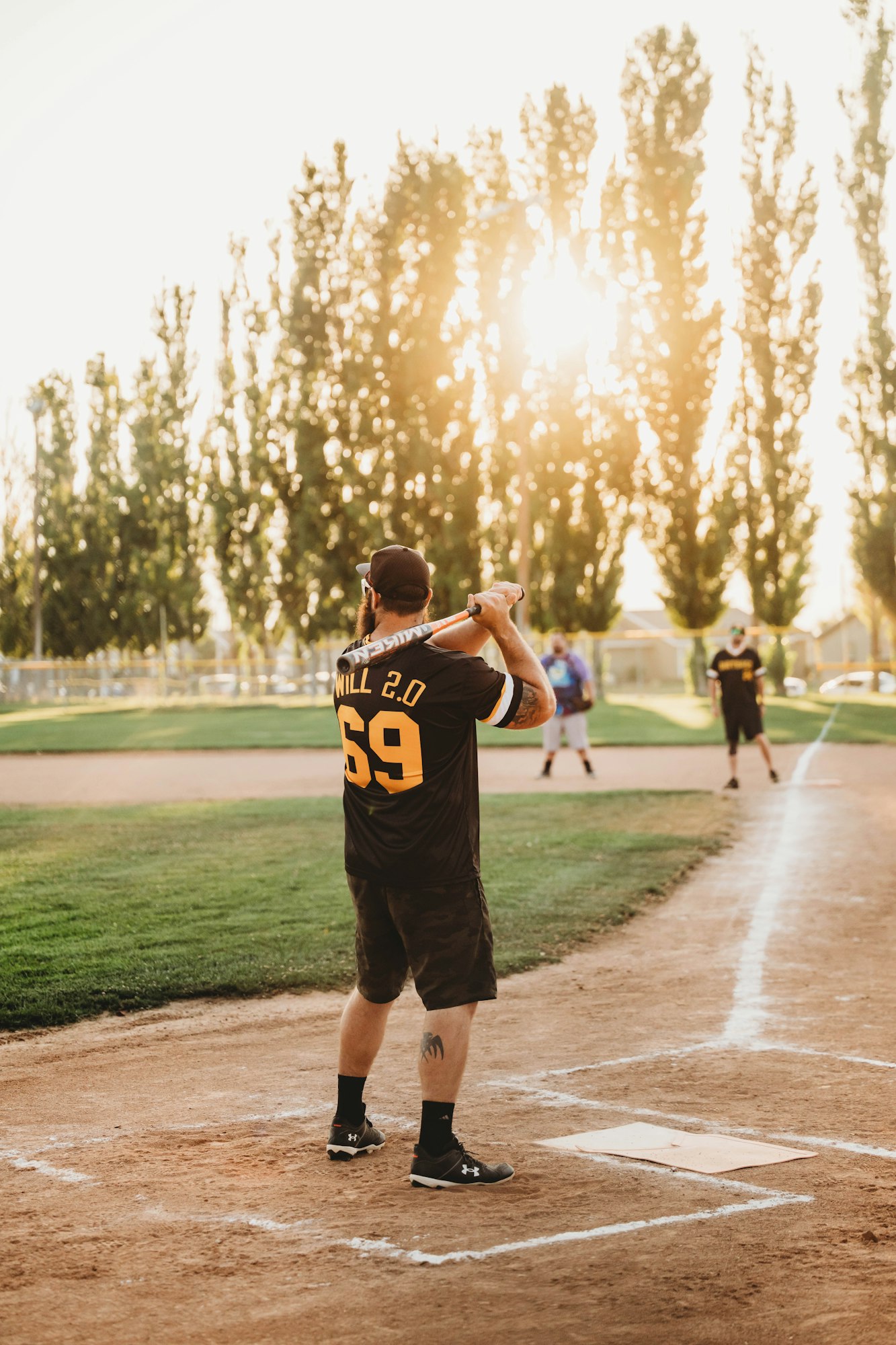 A baseball player preparing to bat with teammates in the background on a sunny day.