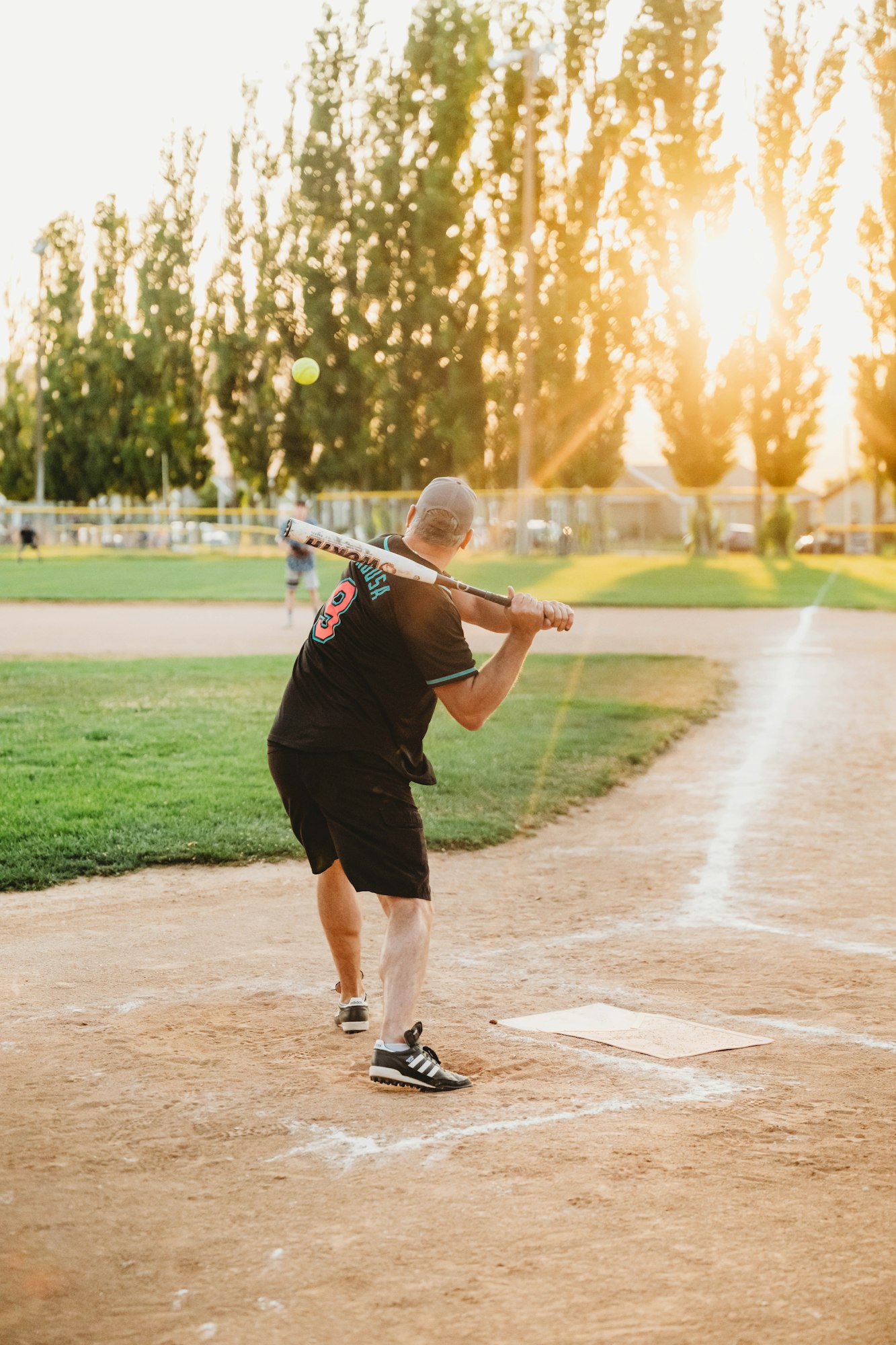 A person playing baseball at sunset on a field.