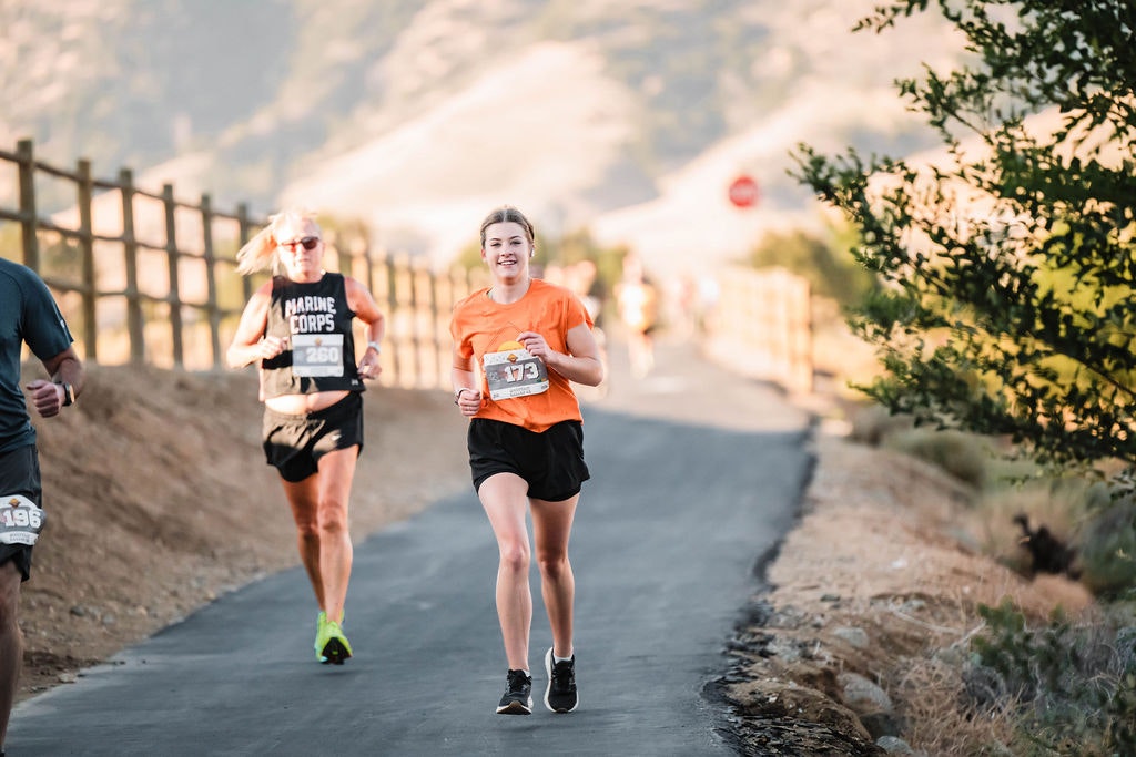 People running on a scenic outdoor path, with race numbers visible.