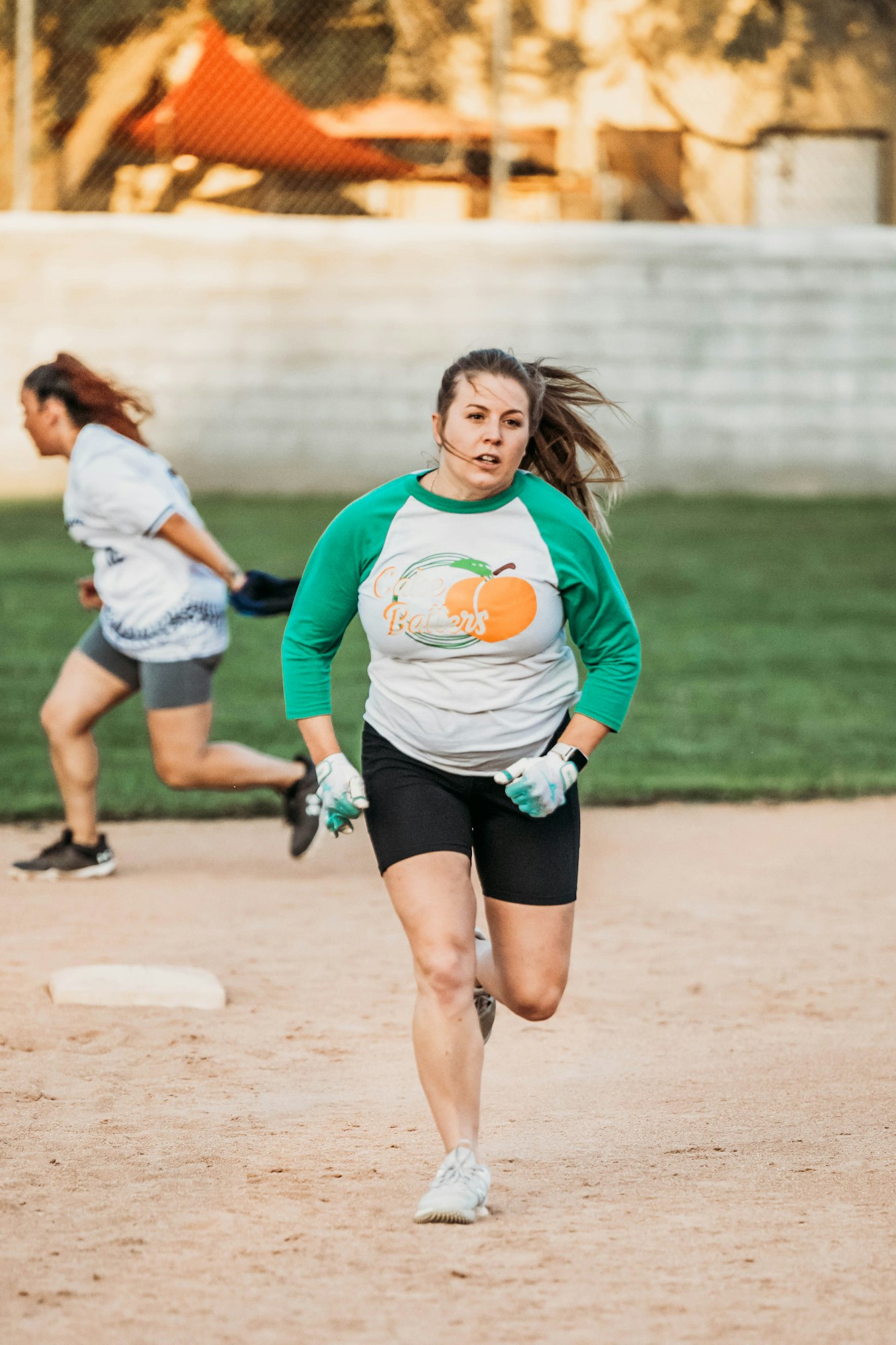 A focused woman playing softball, running bases with intensity.