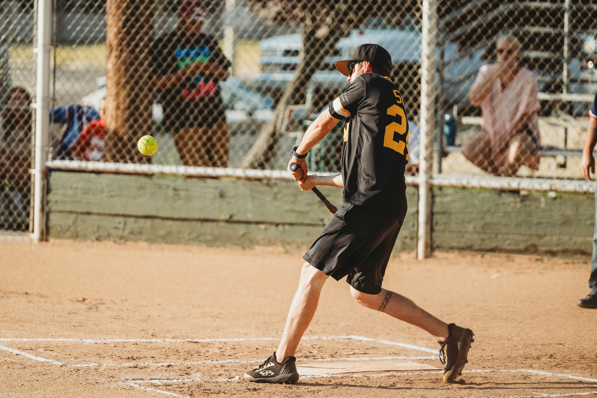 A softball player swinging at a pitch on a sunny day.