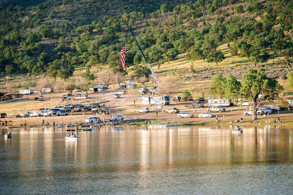 Lakeside RVs, vehicles, people fishing, and a large American flag.