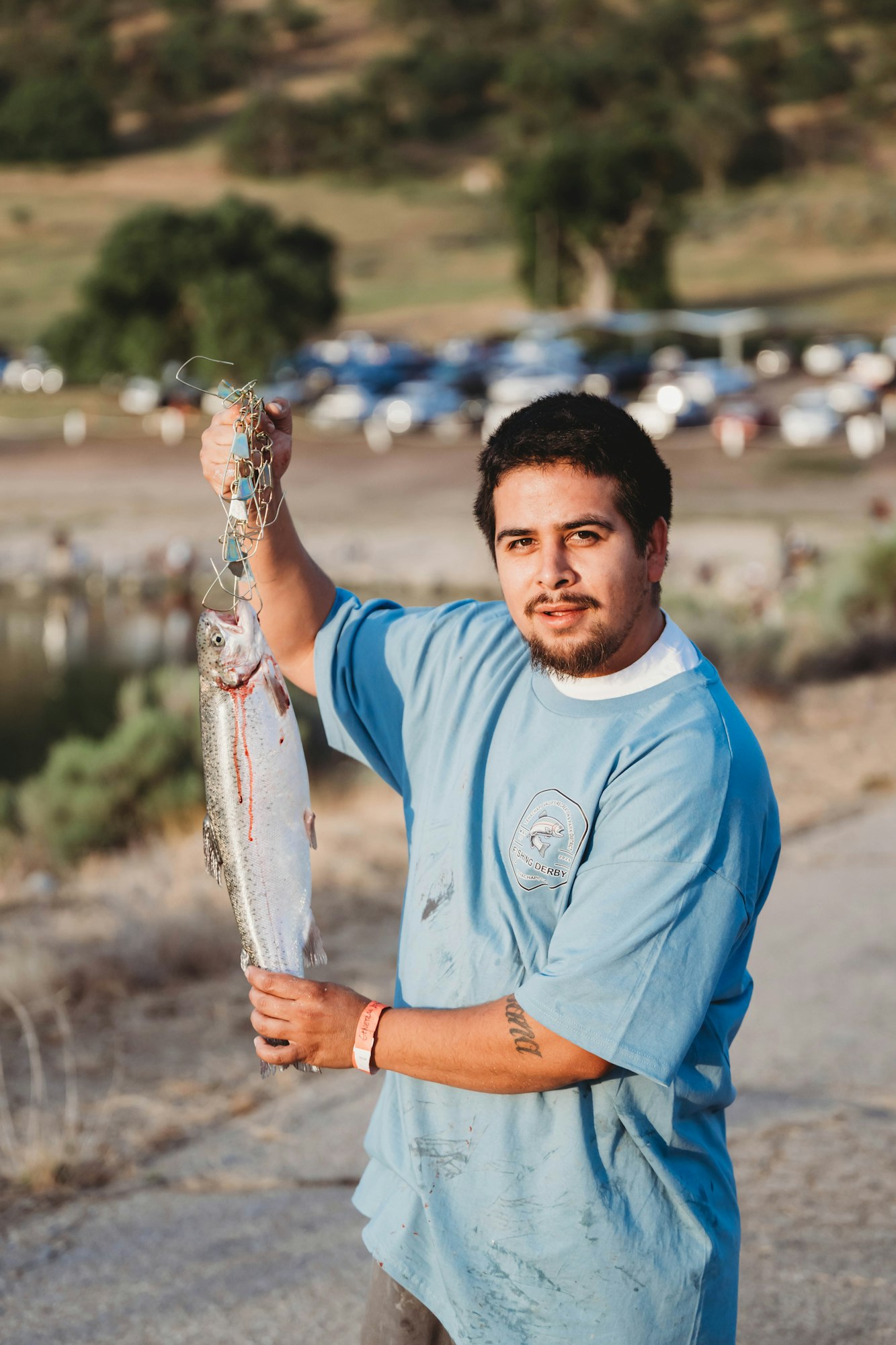 A man in a blue shirt holding a caught fish outdoors.