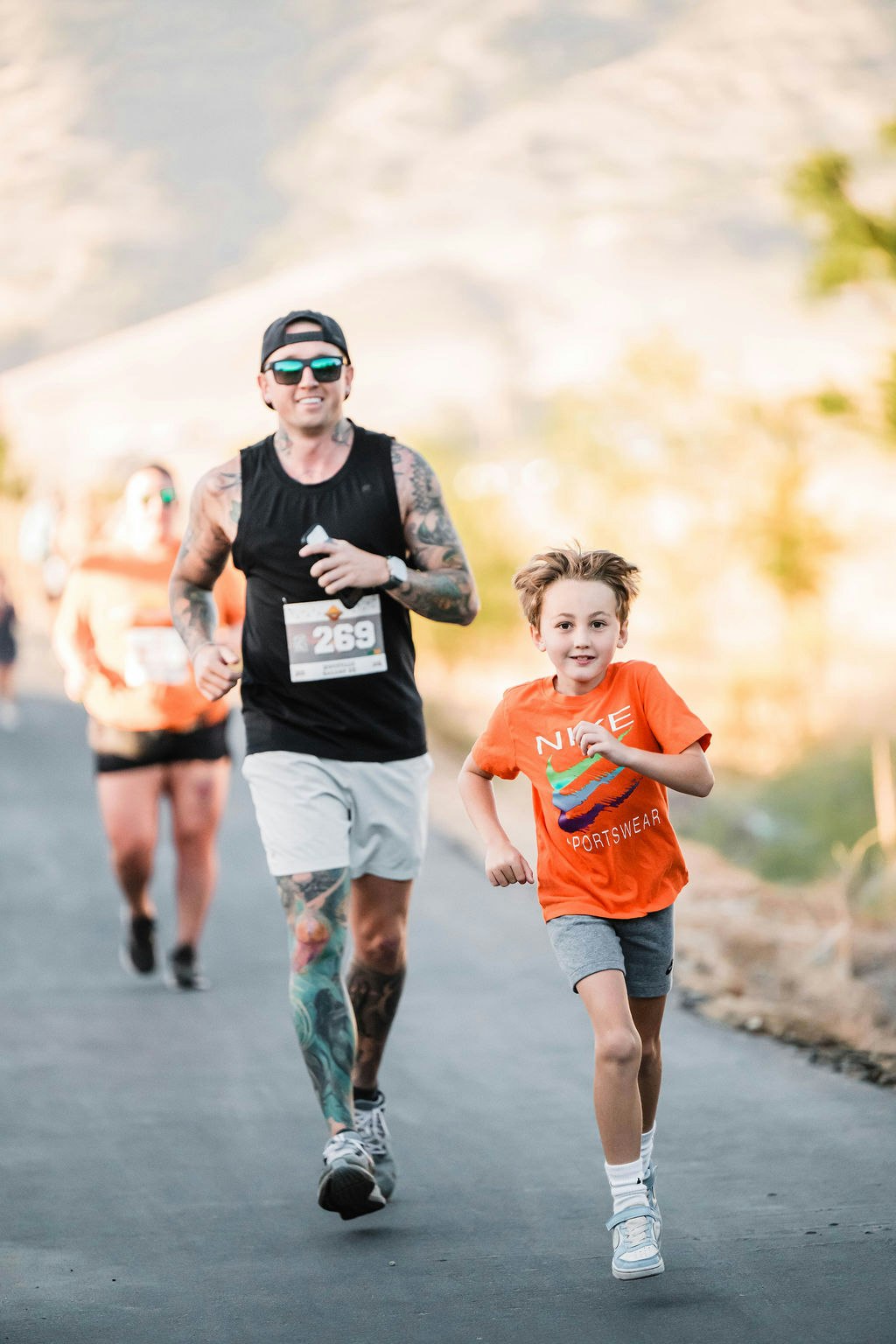 A child and adults running together outdoors, with the child leading, in a casual race.