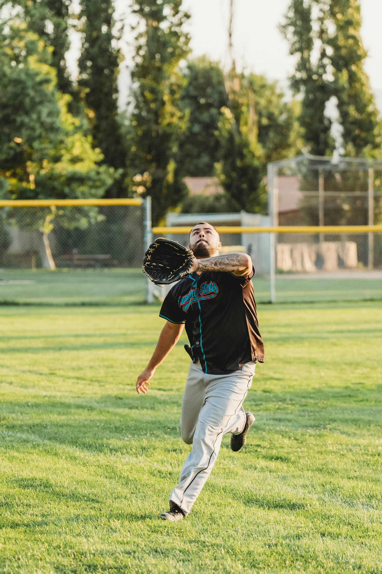 A baseball player is focused on catching a ball in the outfield.