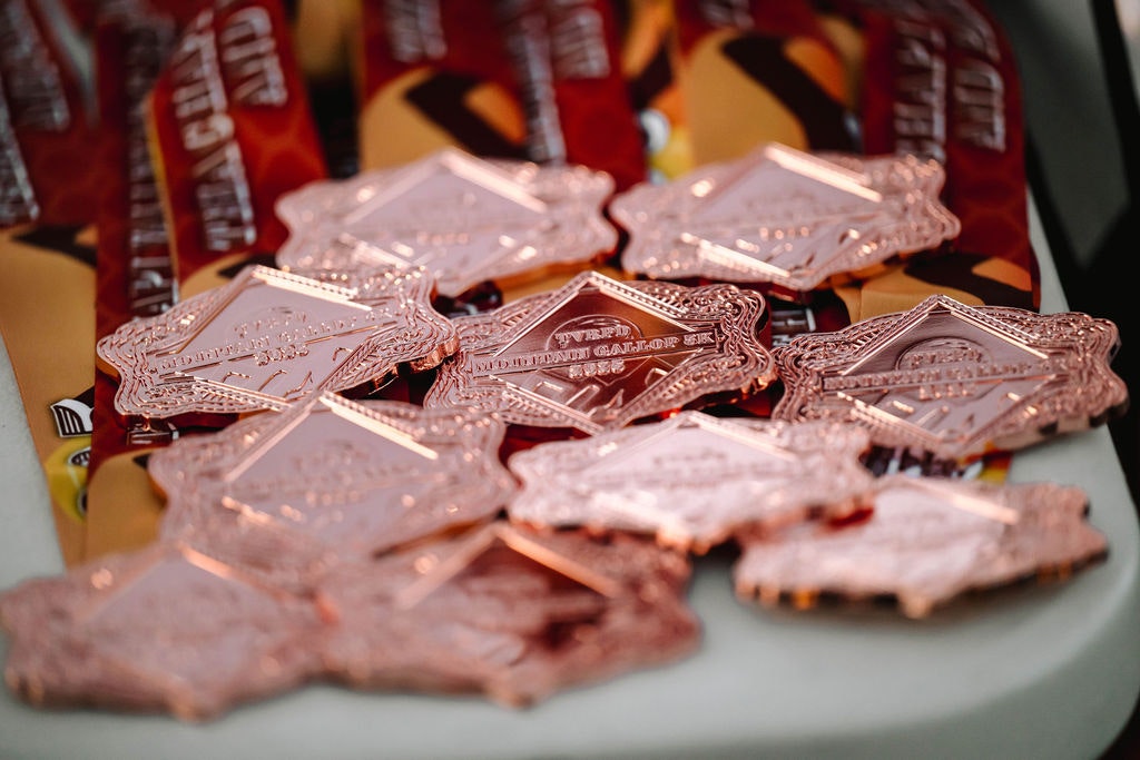 Copper-colored medals with ornate designs placed on top of branded packaging on a table.