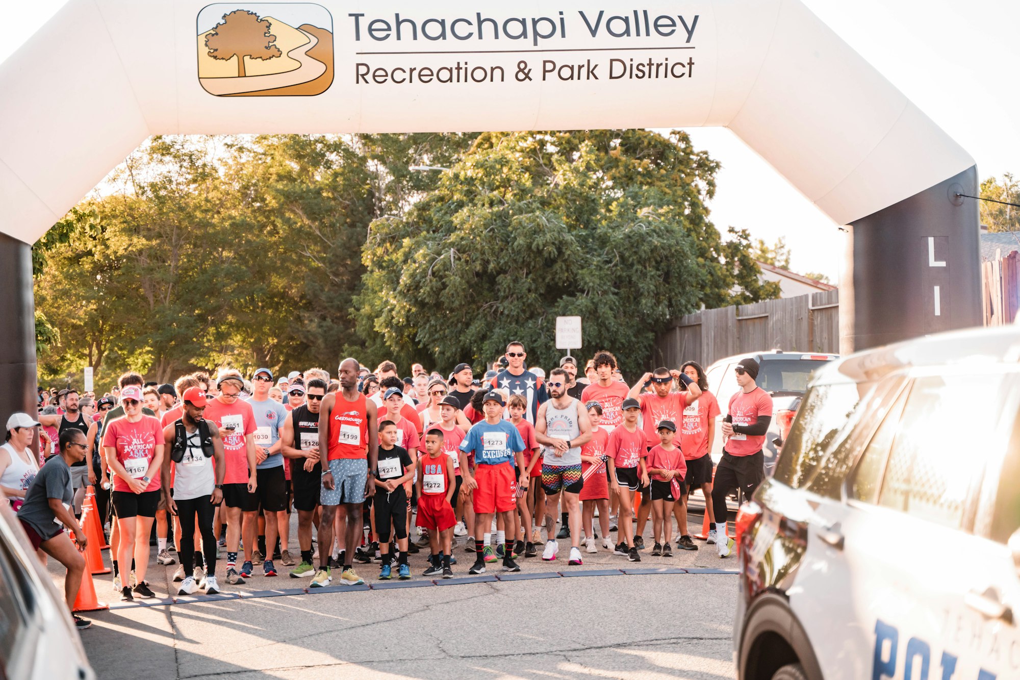A group of people getting ready to start a race under a Tehachapi Valley Recreation & Park District arch.