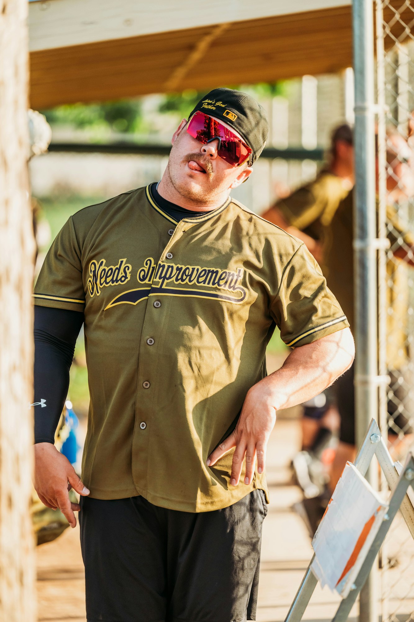 A man in sunglasses and a baseball uniform labeled "Needs Improvement."
