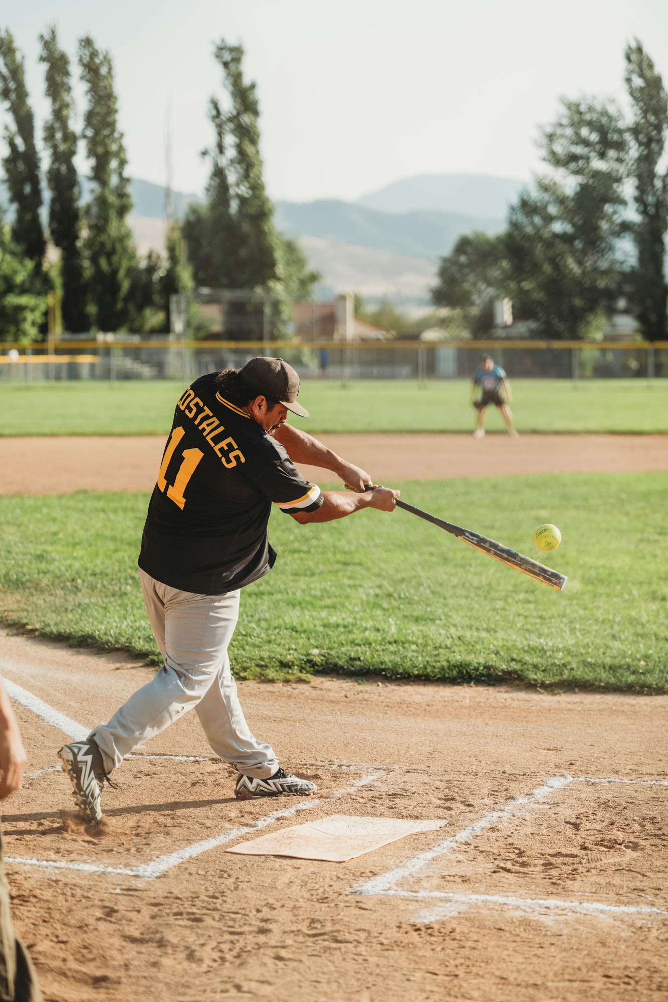 A player swinging a bat at a softball game.