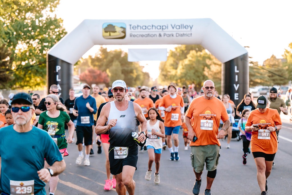 People running in a race under an archway labeled "Tehachapi Valley Recreation & Park District."