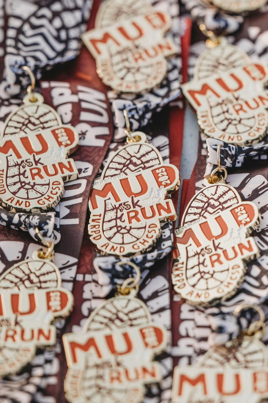 Medals for a mud run event, featuring shoe tread designs and the words "MUD RUN" prominently.
