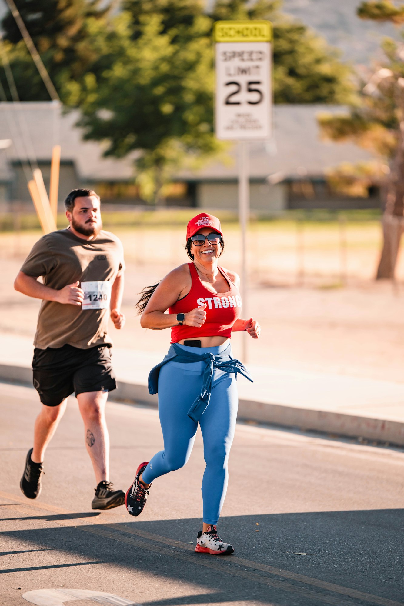 Two people jogging on a road with a speed limit sign in the background.