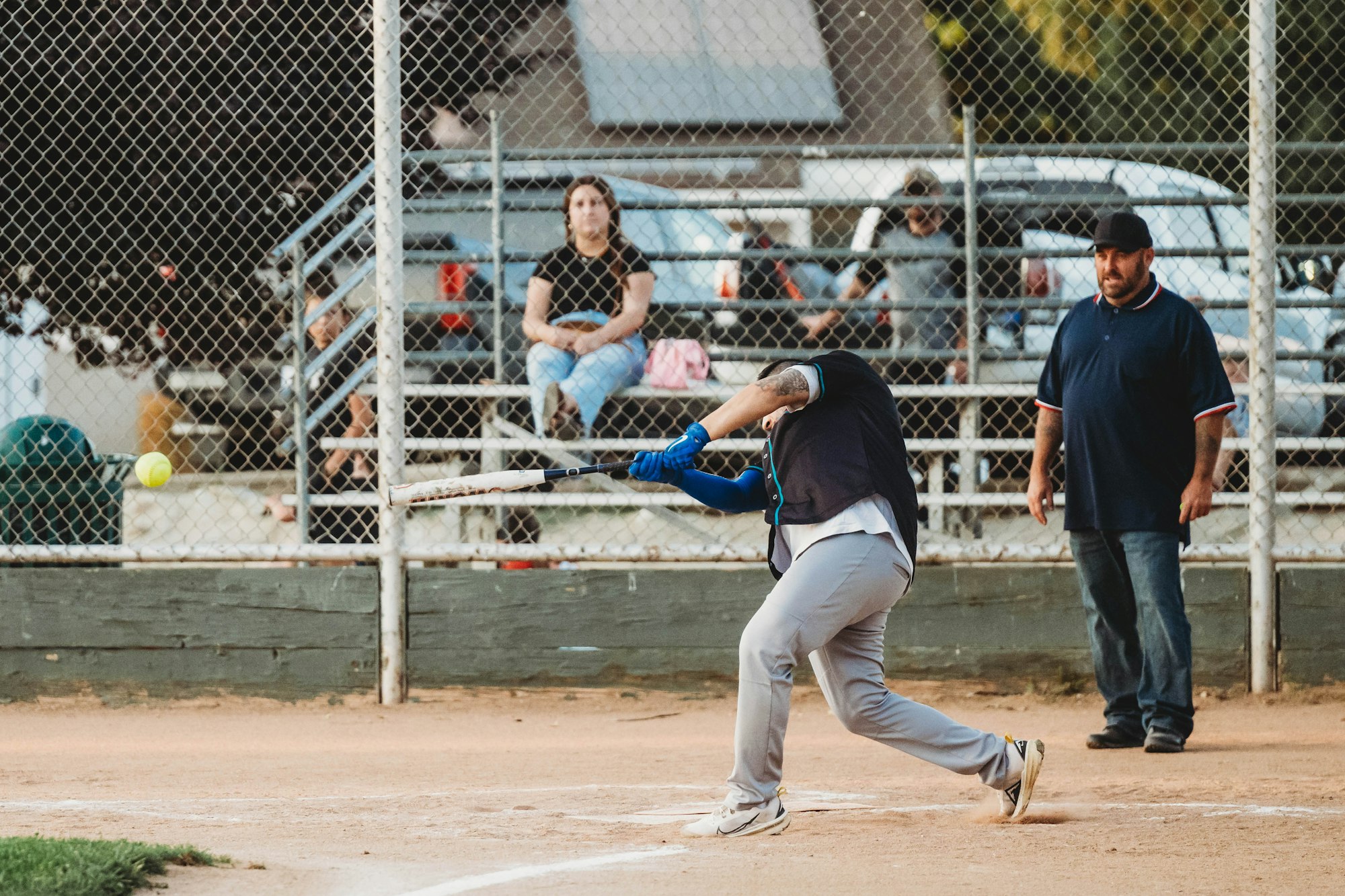 A baseball player swinging at a pitch with a catcher and umpire behind him and spectators in the background.