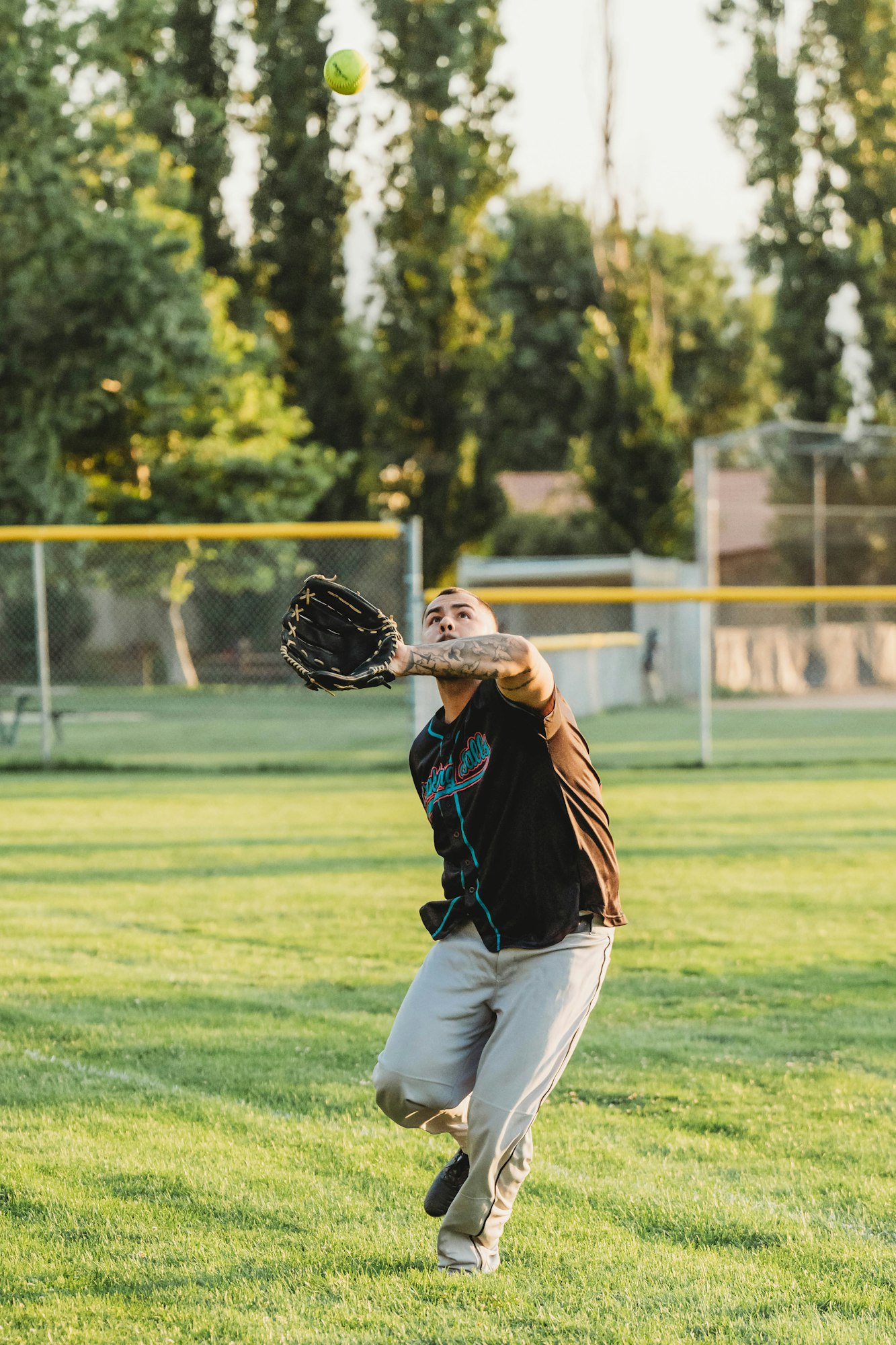 Person catching a softball in a park.