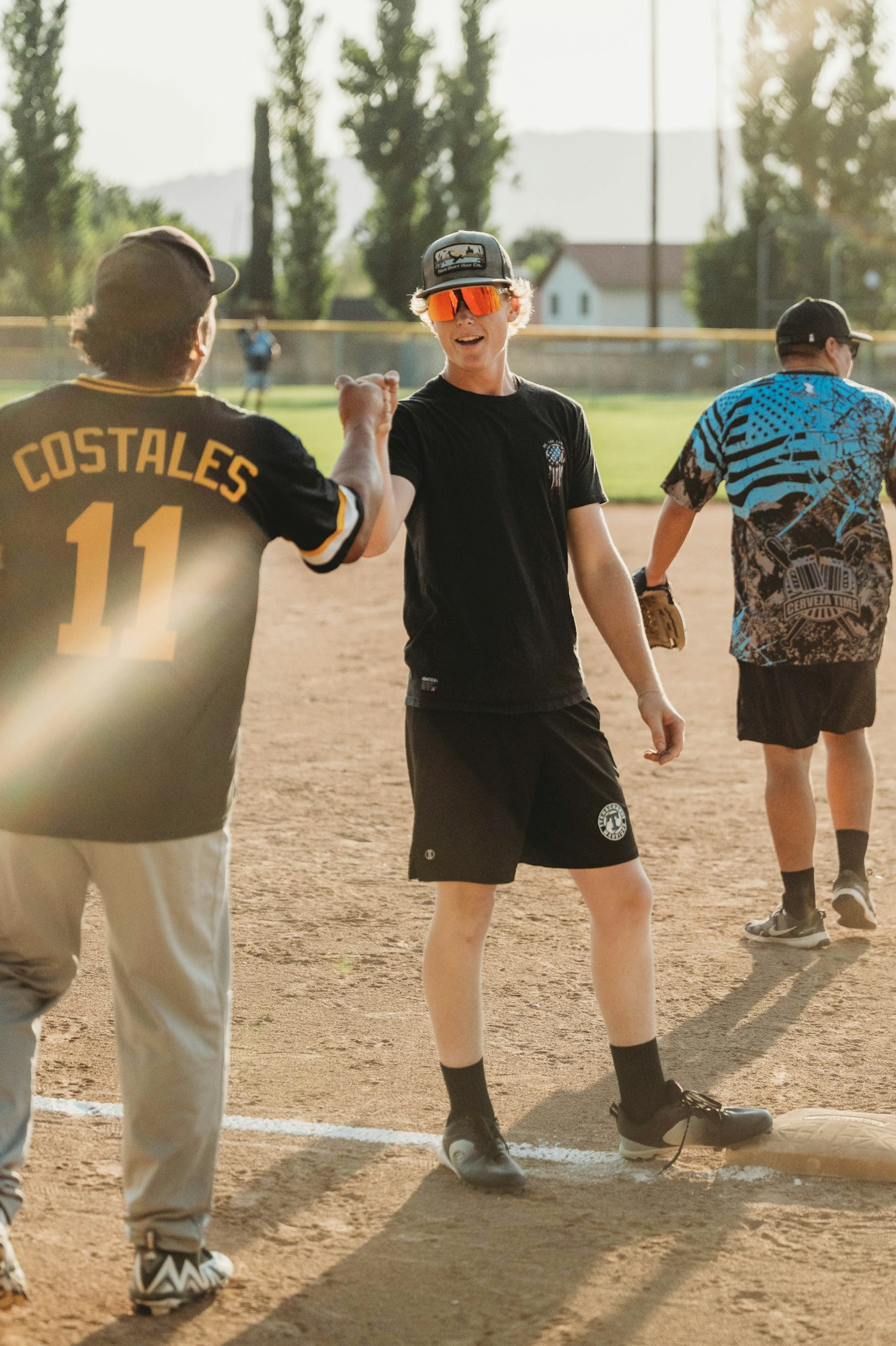 Baseball game moment: a player and a coach celebrate with a fist bump on a dusty field.