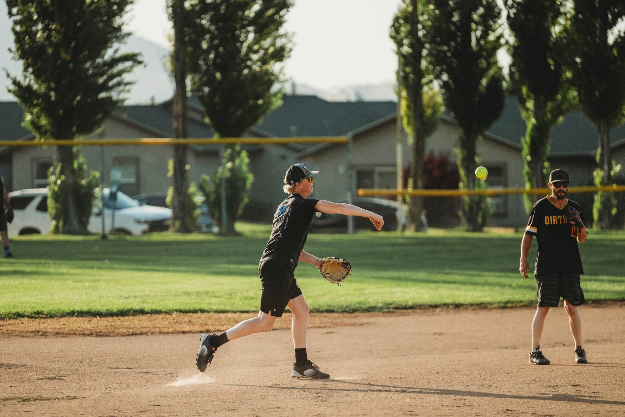 Two people playing baseball, one pitching and the other ready to catch.