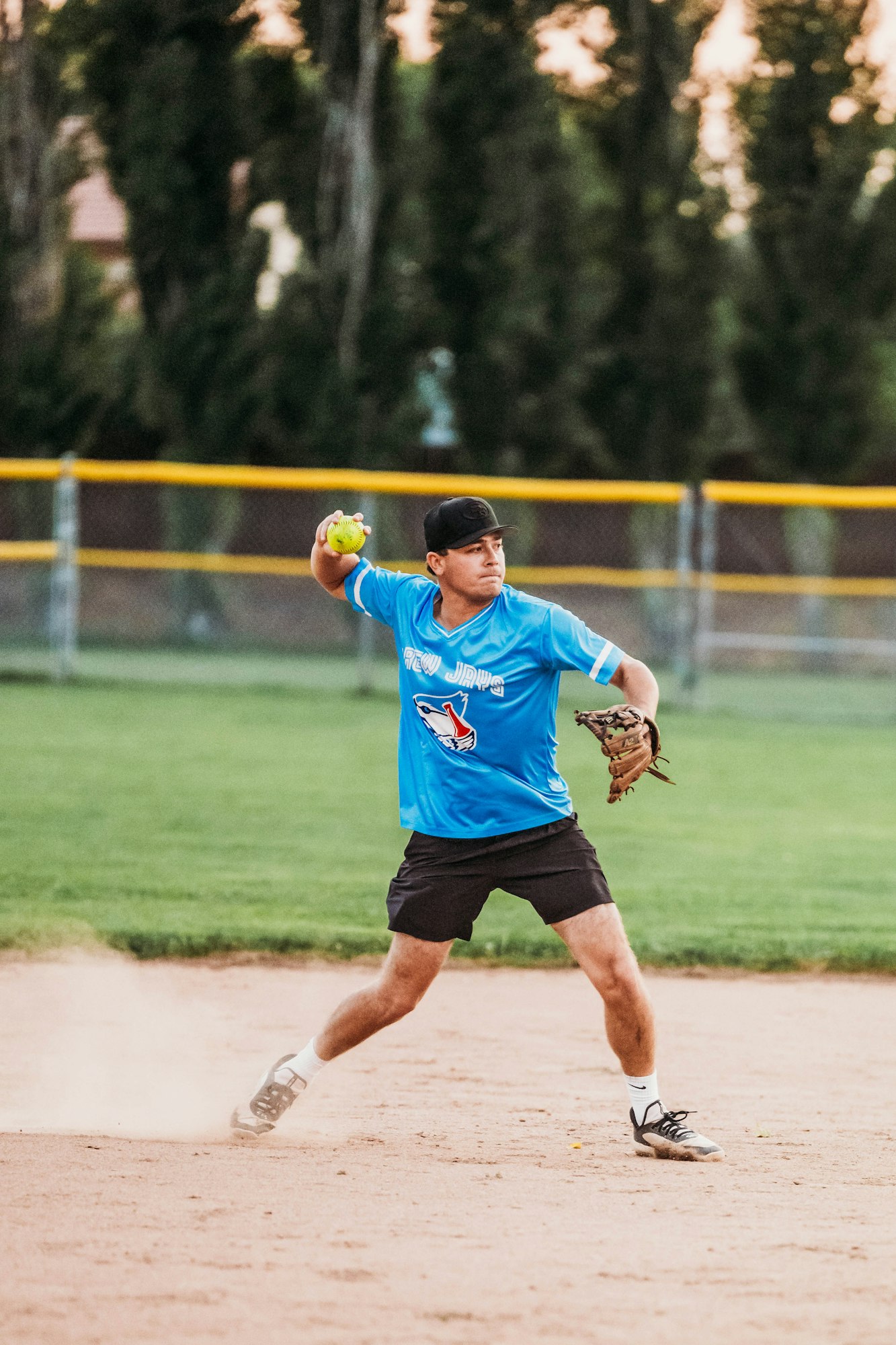 A person throwing a softball on a field.