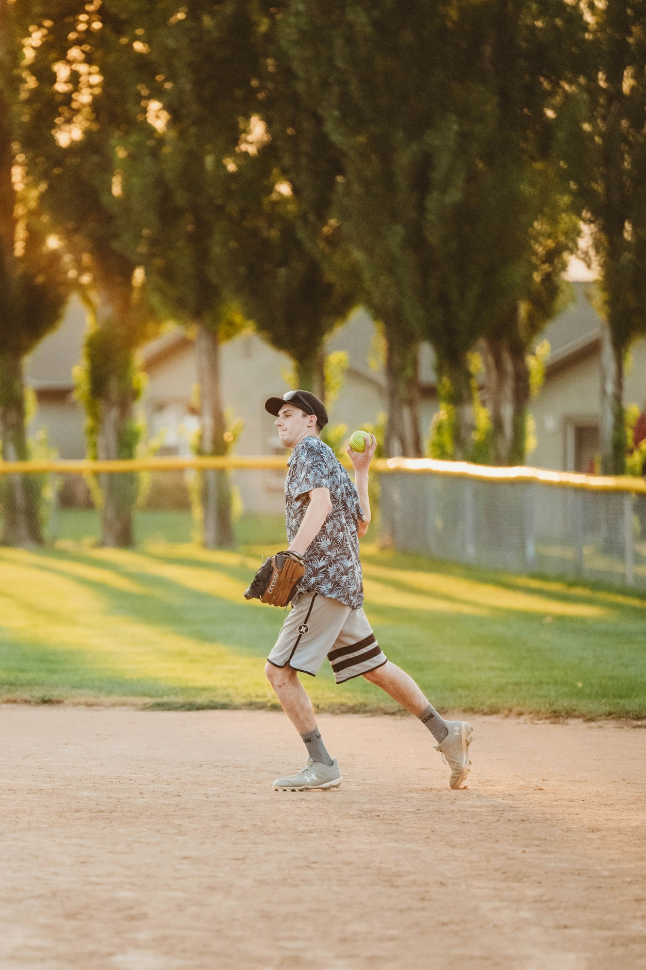 A person playing baseball on a field at dusk.