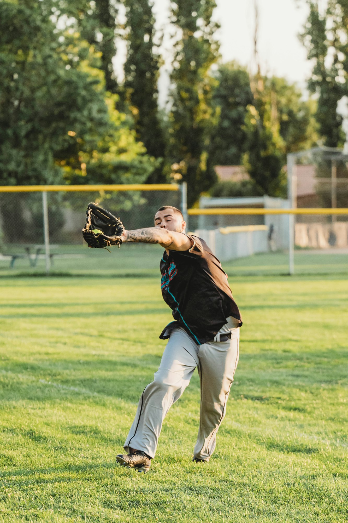 Person playing baseball, catching a ball with a glove.