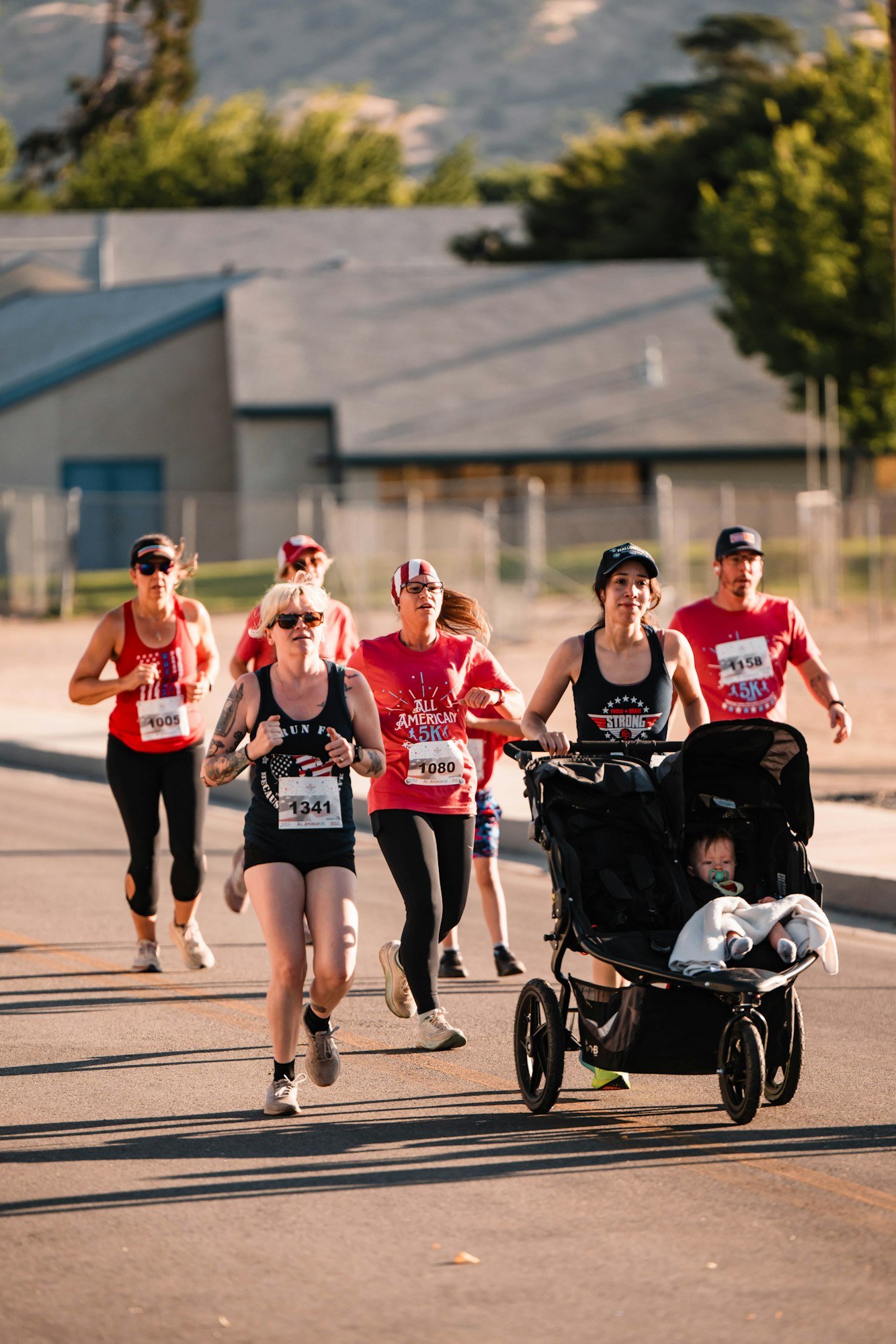 A group of runners in a race, one pushing a stroller with a child.