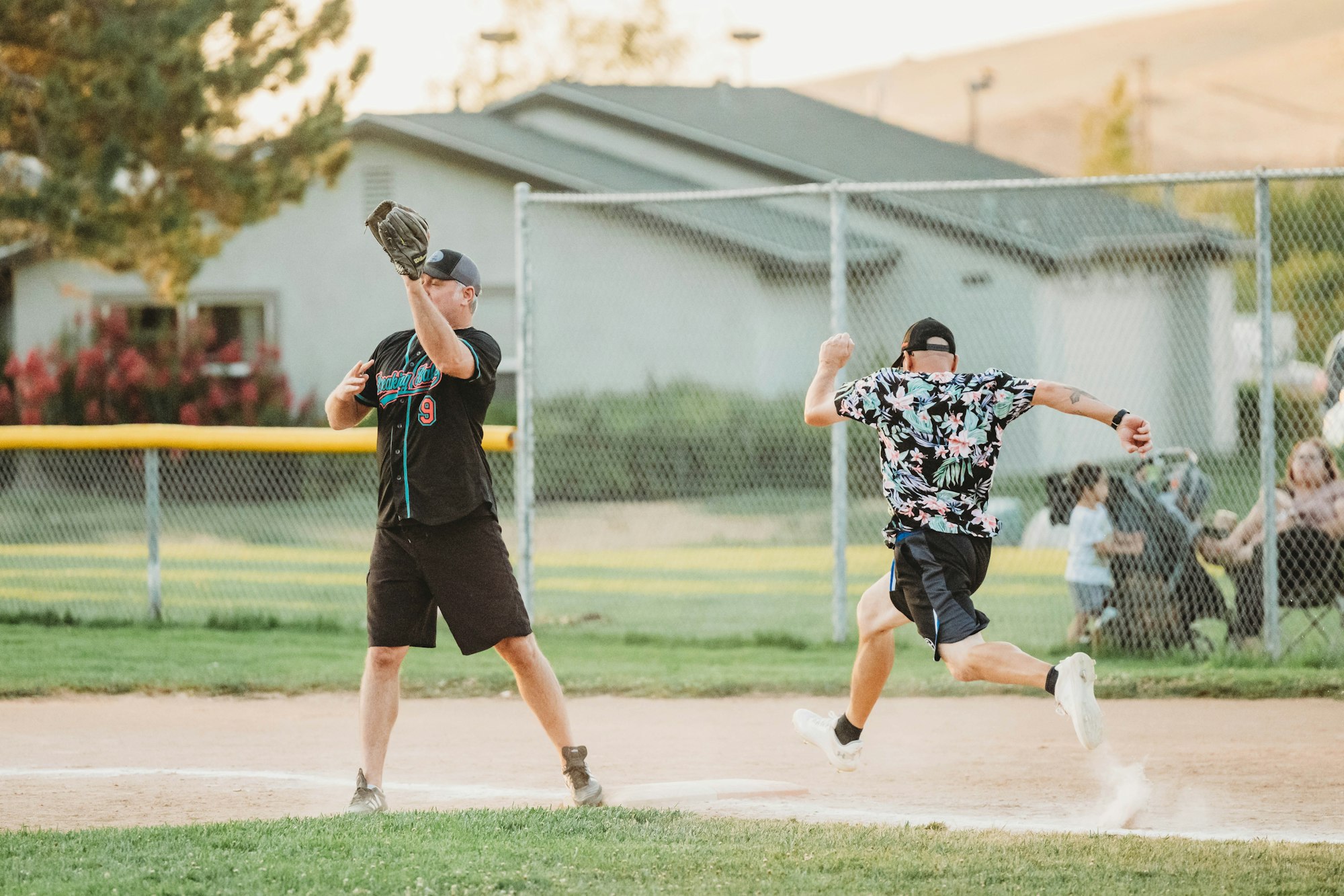 Two players in action during a softball game, one catching, one running.