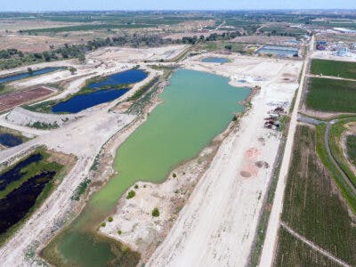 Aerial view of ponds in a landscape with bare land and greenery, possibly indicating industrial or water management areas.