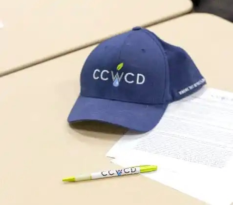 A blue baseball cap with "CCWCD" on it, a pen, and a document on a table.