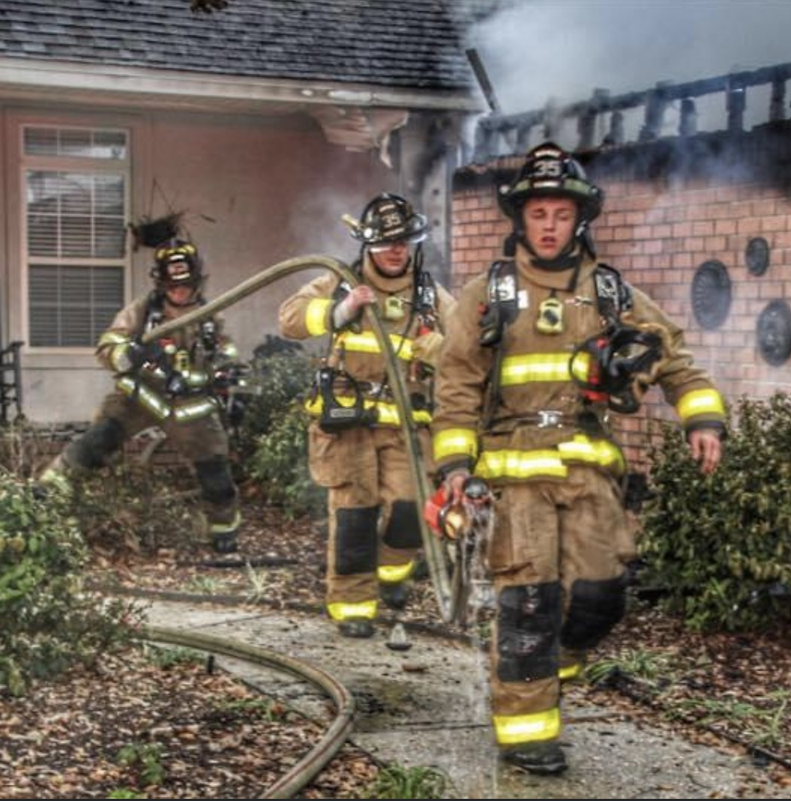 Photo of firefighters carrying a hose
