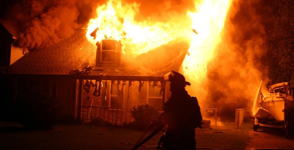 Photo of a house on fire and a firefighter