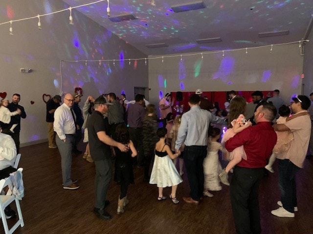 People dancing at an indoor party with colorful lights.