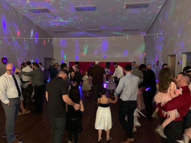 Indoor party with colorful lights and people dancing or socializing.